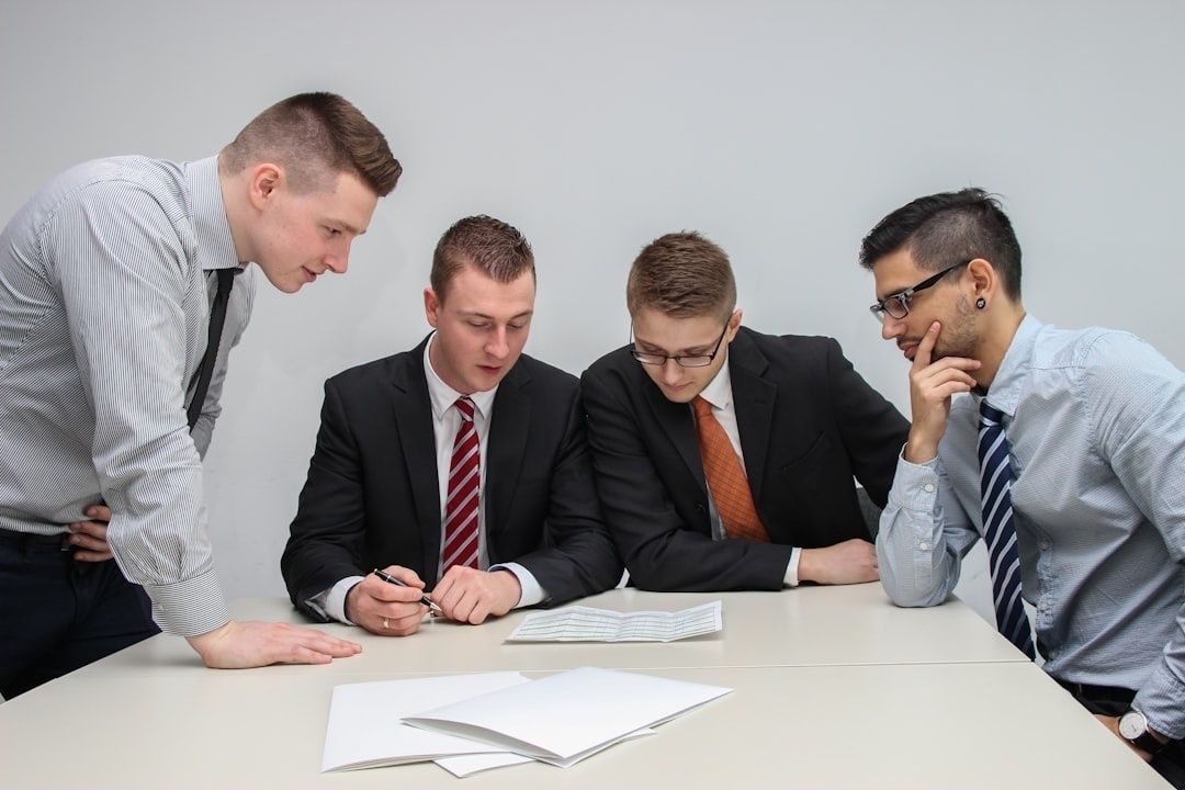 Vier zakenmensen bespreken documenten en grafieken tijdens een overleg